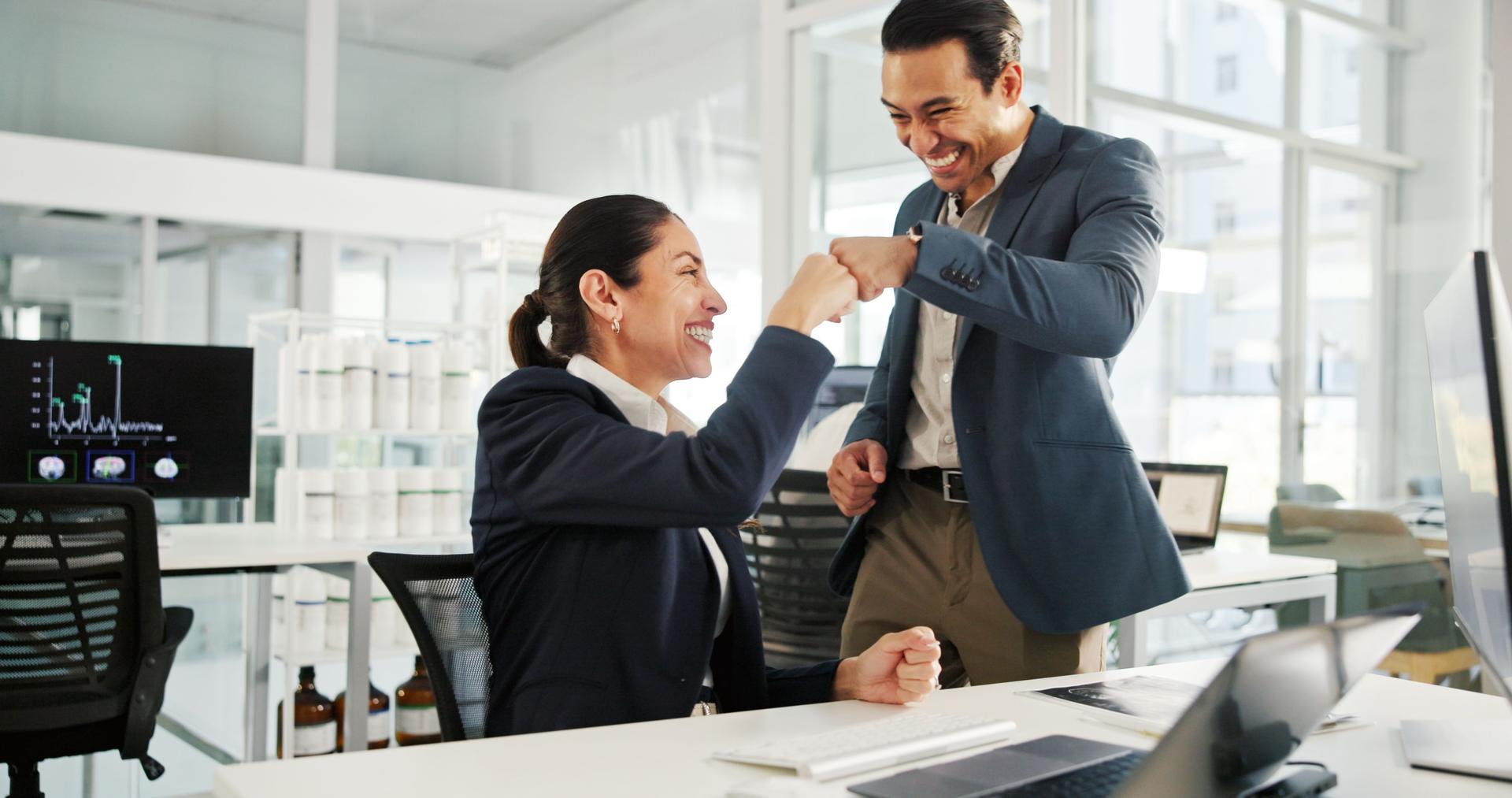 Business people, success and celebration with fist bump at office for neurology study, results or good news. Businessman, woman or employees with smile for medical investment, profit or teamwork